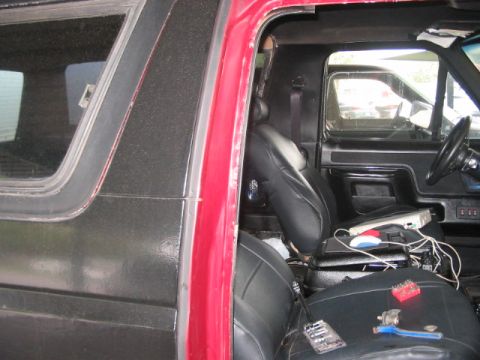 1991 Ford Bronco - The interior of a vehicle shows black leather seats and a dashboard with tools scattered on the seats.