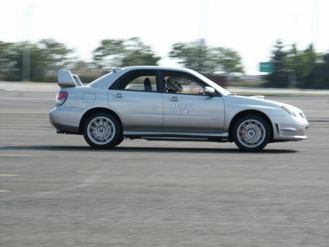 2001 Mercury Grand Marquis - Silver Subaru Impreza WRX STI sedan with racing number 879 on the door, seen on a race track.