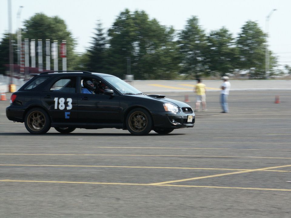 Black station wagon with number 183 on the side, on a race track