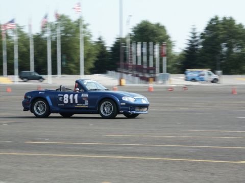 2001 Mercury Grand Marquis - A blue convertible sports car, identified by racing number 811, navigates a track on a sunny day.