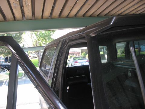 1991 Ford Bronco - View from outside an open door into the interior of a dark-colored SUV, with a glimpse of other vehicles outside.