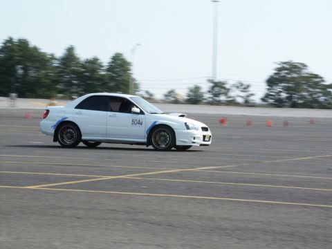 2001 Mercury Grand Marquis - A white Subaru WRX navigates a course marked by traffic cones, with the number '504u' visible on its door.