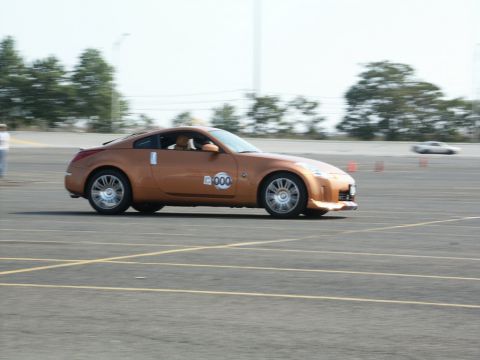 2001 Mercury Grand Marquis - An orange sports car navigates a track, with another vehicle blurred in the background.