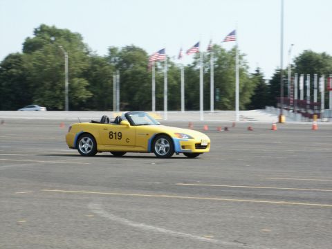 2001 Mercury Grand Marquis - A yellow convertible sports car navigates a course marked by orange cones under a bright sky.