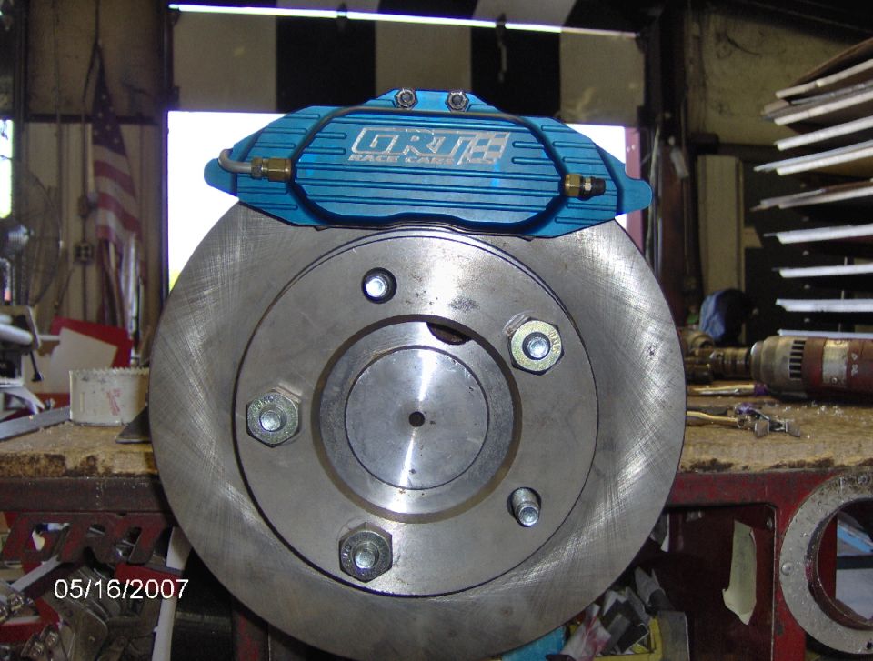 Brake rotor with a blue racing caliper on a workbench