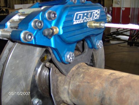 1978 Ford Bronco - Close-up of a blue GRT Race Cars brake caliper assembly on a rusty axle.