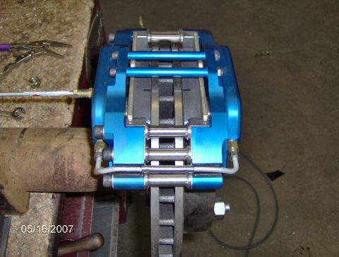1978 Ford Bronco - A close-up view of a blue brake caliper assembly attached to a brake rotor.