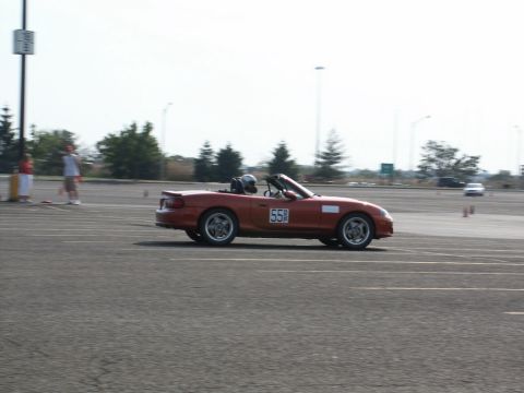 2001 Mercury Grand Marquis - A red convertible sports car with racing number 55 is captured in motion on a track, likely during a motorsports event.