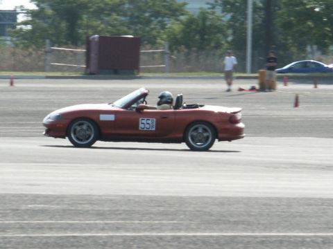 2001 Mercury Grand Marquis - A red convertible is seen on a race track with a driver wearing a helmet.