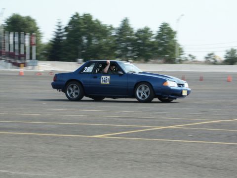 2001 Mercury Grand Marquis - A blue Ford Mustang is seen on a race track, displaying racing numbers on its doors and windows.