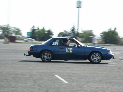 2001 Mercury Grand Marquis - A blue coupe race car with racing numbers is captured in motion on an asphalt track.