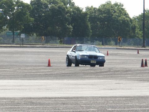 2001 Mercury Grand Marquis - Ford Mustang navigates a cone course on a paved lot, suggesting a track day or autocross event.