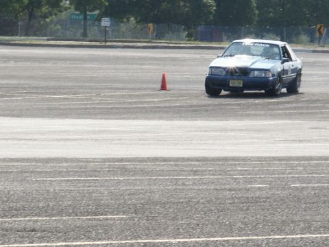 2001 Mercury Grand Marquis - A blue coupe, possibly a Ford Mustang, navigates a course marked by traffic cones on a sunny day.