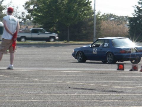 2001 Mercury Grand Marquis - A blue coupe with racing numbers drives on a track, with a pickup truck in the background.