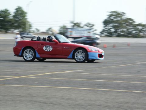 2001 Mercury Grand Marquis - A red convertible sports car with blue accents and racing number 353 is seen on a race track with another vehicle in the background.