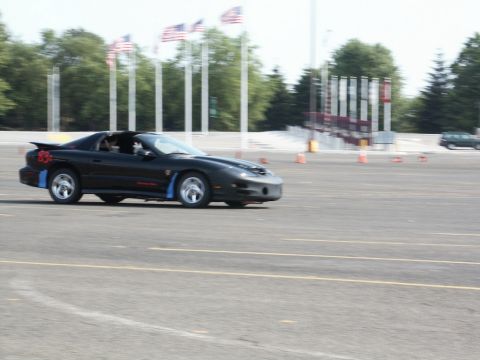 2001 Mercury Grand Marquis - Black Pontiac Firebird driving on a track, with American flags visible.