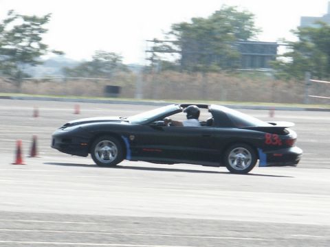 2001 Mercury Grand Marquis - A black Pontiac Firebird Trans Am convertible navigates a course marked by orange cones, with a driver in a helmet at the wheel.