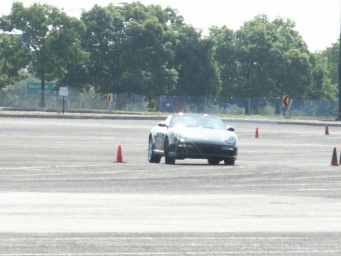 2001 Mercury Grand Marquis - A dark convertible sports car is seen on a track, maneuvering around orange cones.