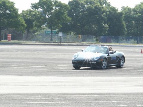 2001 Mercury Grand Marquis - A black Porsche Boxster convertible is seen on an asphalt track with trees in the background.