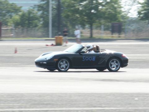 2001 Mercury Grand Marquis - A black convertible sports car, identified by the blue lettering 'SOOB' on its side, is seen on a track with a driver wearing a helmet.