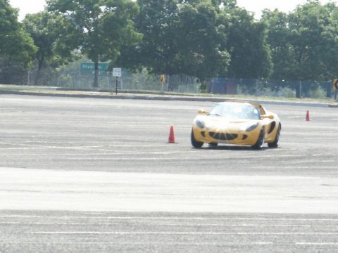 2001 Mercury Grand Marquis - A yellow sports car navigates a course marked by orange cones on a paved surface.