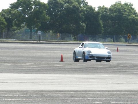 2001 Mercury Grand Marquis - A white Porsche 911 navigates a course marked by orange cones on a paved lot.