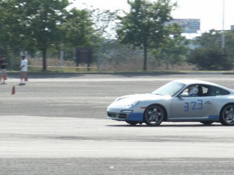 2001 Mercury Grand Marquis - A silver Porsche 911 with blue racing stripes and the number 323 is seen on a track, with a driver wearing a helmet.
