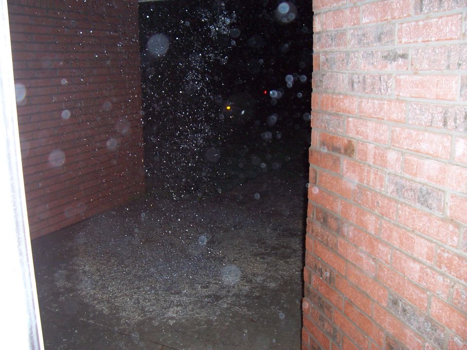 Brick wall and dark outdoor area with many small white particles falling