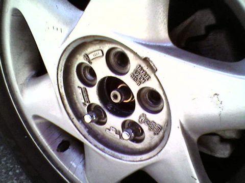 1993 Ford Taurus - A detailed view of a car's alloy wheel, showing the lug nut mounting points and some manufacturing text.