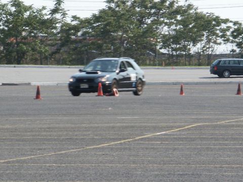 2001 Mercury Grand Marquis - A black Subaru Impreza WRX hatchback navigates a course marked by orange cones.