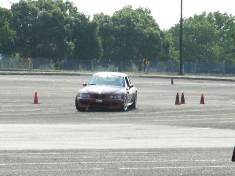 2001 Mercury Grand Marquis - A red BMW Z3 coupe navigates an autocross course marked by orange cones.