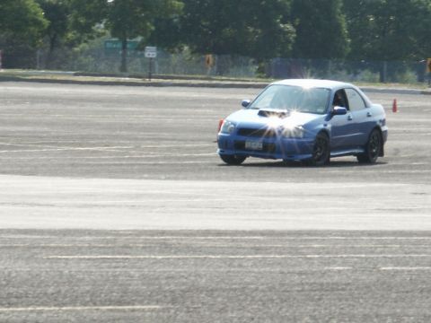 2001 Mercury Grand Marquis - A blue Subaru Impreza WRX is seen on a paved surface, possibly during a track event or autocross.