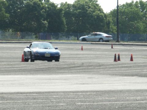 2001 Mercury Grand Marquis - A blue sports car navigates a course marked by orange cones on a sunny day.