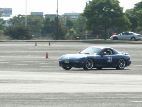 2001 Mercury Grand Marquis - A blue sports car with racing numbers on its door navigates a course marked by traffic cones, with another car visible in the background.