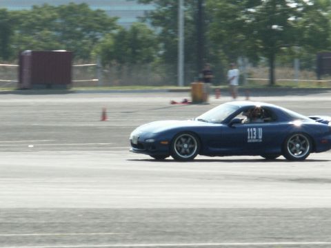 2001 Mercury Grand Marquis - Sports car navigates a track, indicated by cones and a driver visible inside.