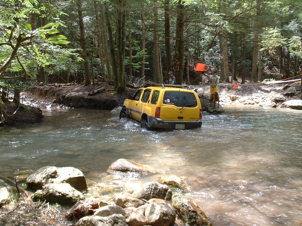 Yellow SUV driving through a river, rear view