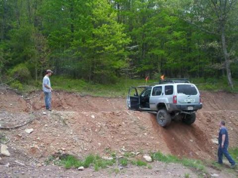 1991 Ford Bronco - A silver SUV navigates a challenging dirt hill with two men observing the off-road activity.