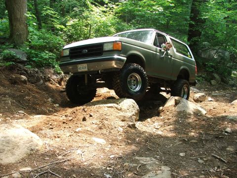 1996 Ford Bronco - This lifted Ford Bronco navigates a challenging rocky path in a wooded area.