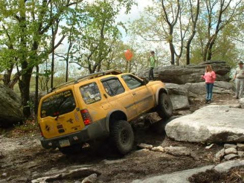 1991 Ford Bronco - SUV attempts to climb over large rocks on a challenging off-road course.