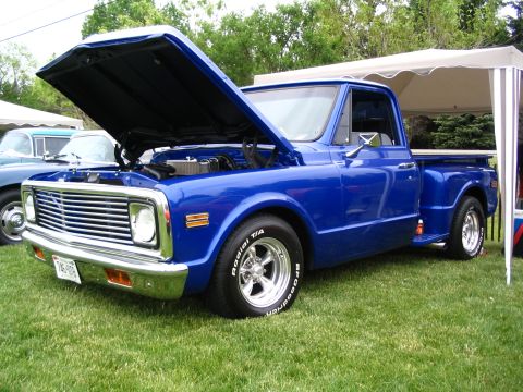 1993 Ford Taurus - A classic blue pickup truck is displayed with its hood open, parked on a grassy lawn under a canopy.