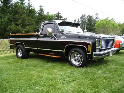 1993 Ford Taurus - A classic black pickup truck is displayed on a grassy field at an outdoor car show.