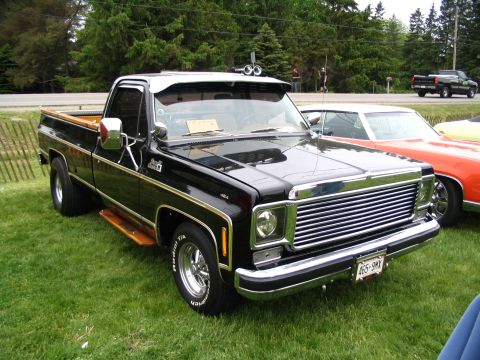1993 Ford Taurus - A black pickup truck with wood trim and chrome accents is displayed at a car show.