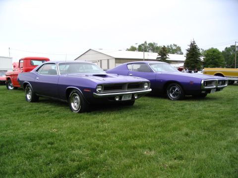 1993 Ford Taurus - Two classic purple muscle cars displayed at an outdoor car show event.