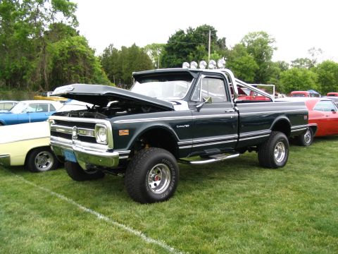 1993 Ford Taurus - A lifted 1970s pickup truck is displayed on a grassy field with other vehicles present.