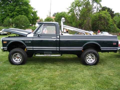 1993 Ford Taurus - A dark green 1971 Chevrolet C10 pickup truck is displayed at a car show, a prominent chrome roll bar and lifted suspension.