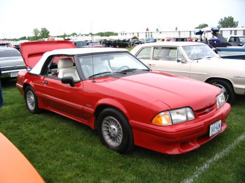 1993 Ford Taurus - Red convertible parked on grass at a car show with other vehicles in the background.