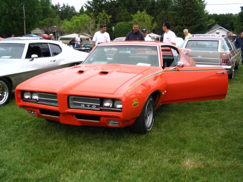 1993 Ford Taurus - A classic orange Pontiac GTO is displayed at an outdoor car show.