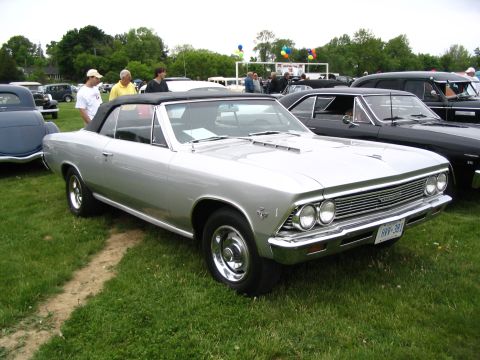 1993 Ford Taurus - A classic silver convertible is displayed at an outdoor car show with other vehicles in the background.