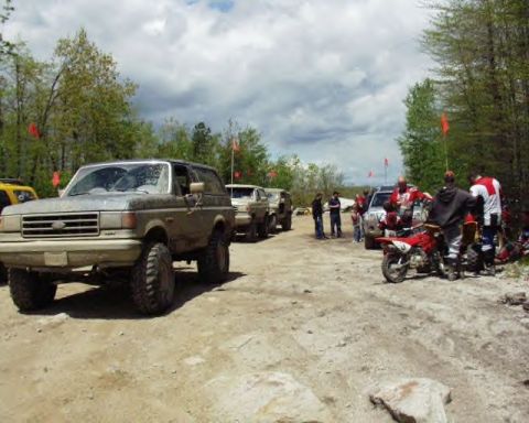 1991 Ford Bronco - Group gathered around vehicles and dirt bikes at an outdoor event.