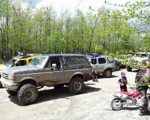 1991 Ford Bronco - A group of off-road vehicles are gathered in a wooded area.
